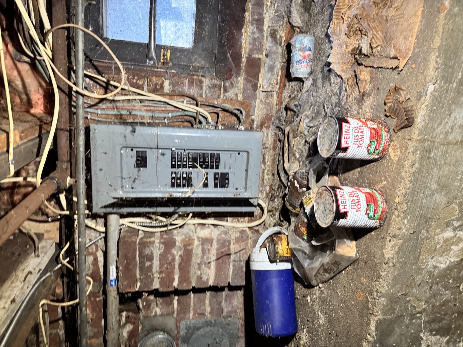 Basement electrical panel with knob-and-tube wiring against an old brick wall
