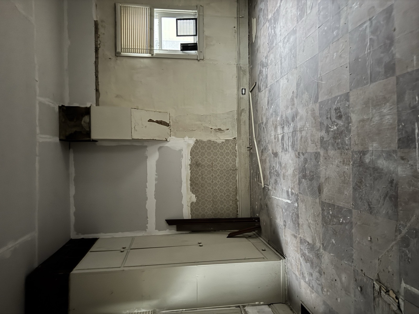 Kitchen stripped back, stained wallpaper still on the walls